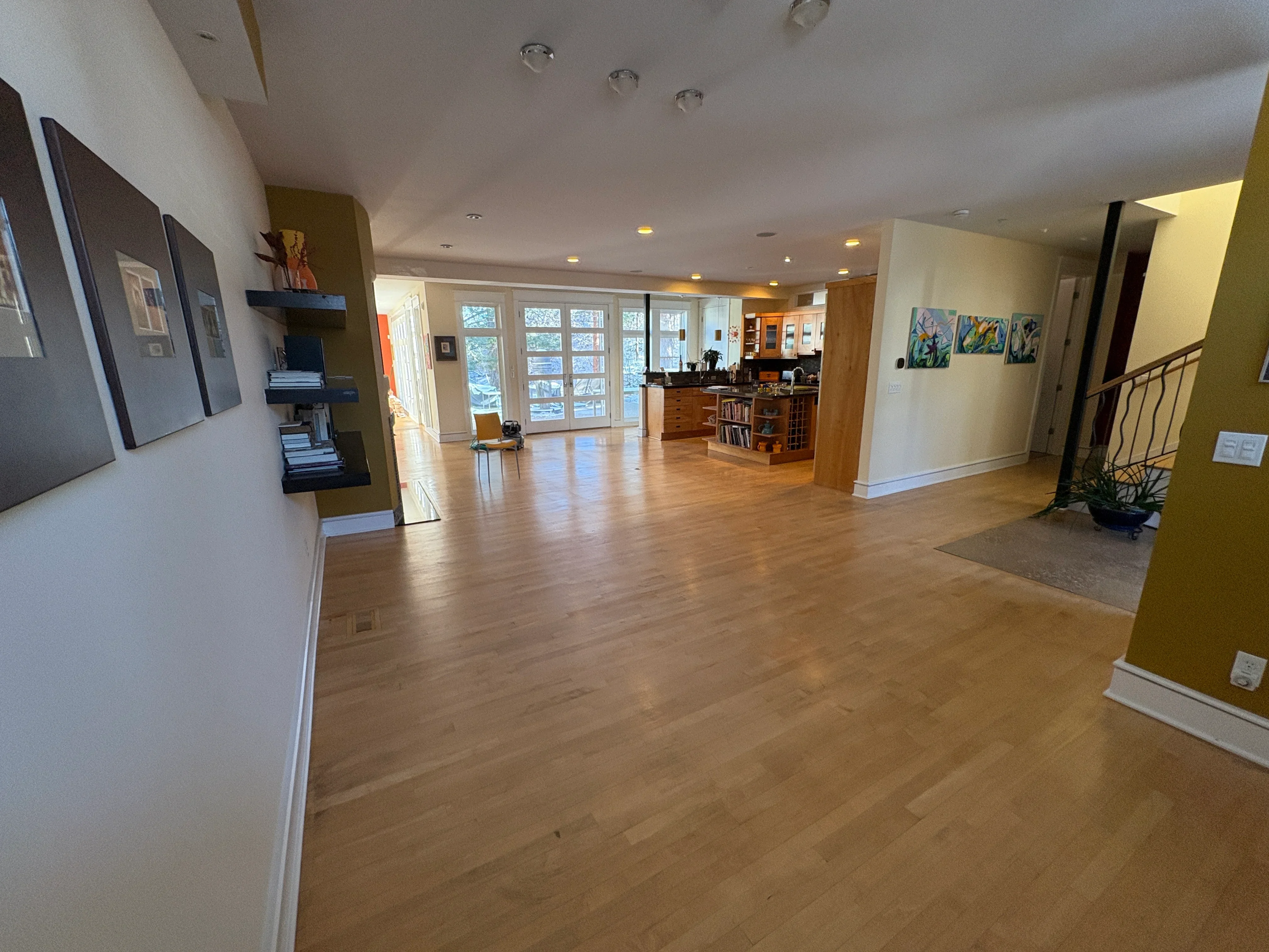 Medium-tone hardwood flooring in open concept home with white trim and recessed lighting