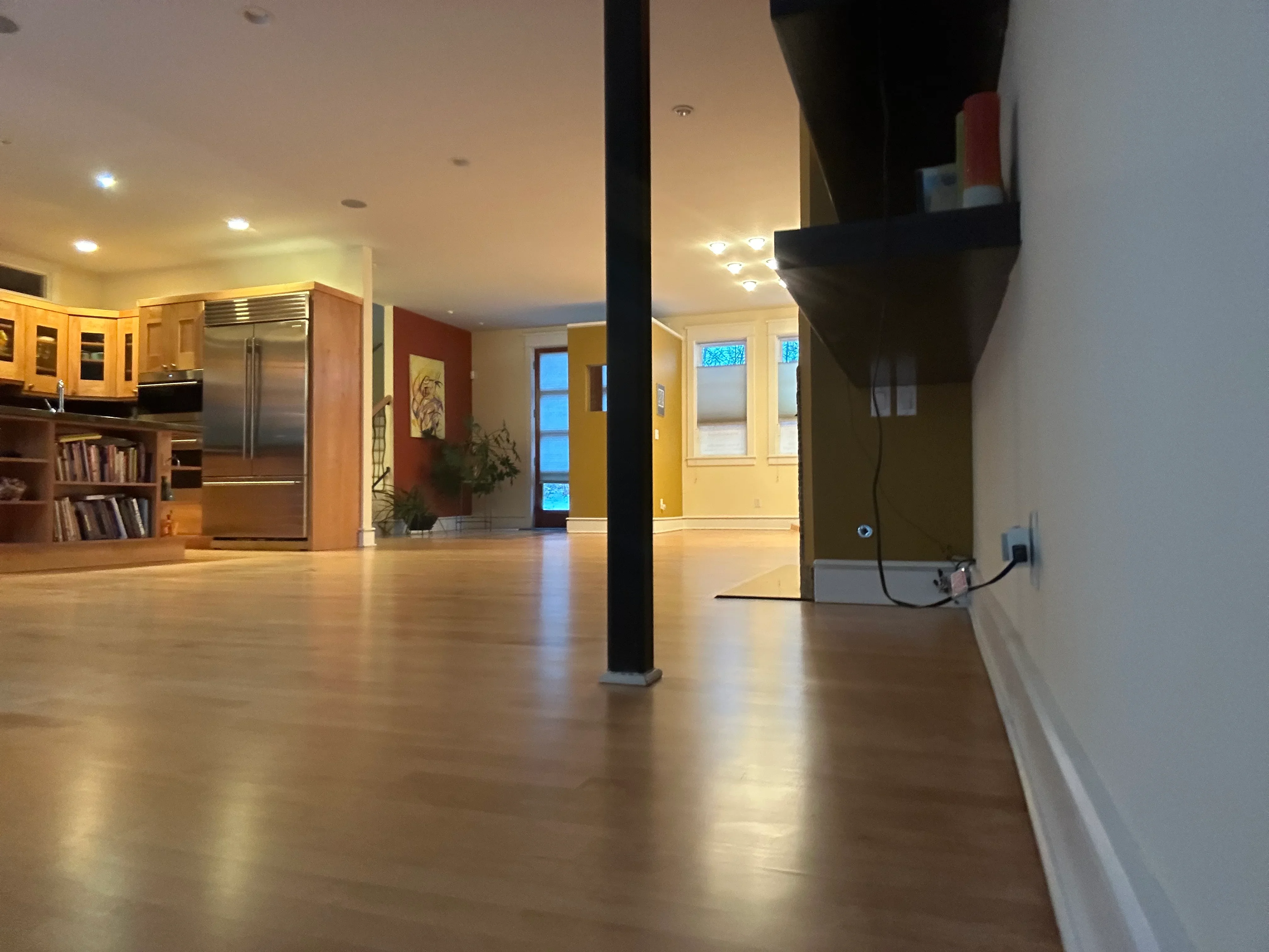 Polished hardwood flooring in open-concept space with wood cabinetry and support column