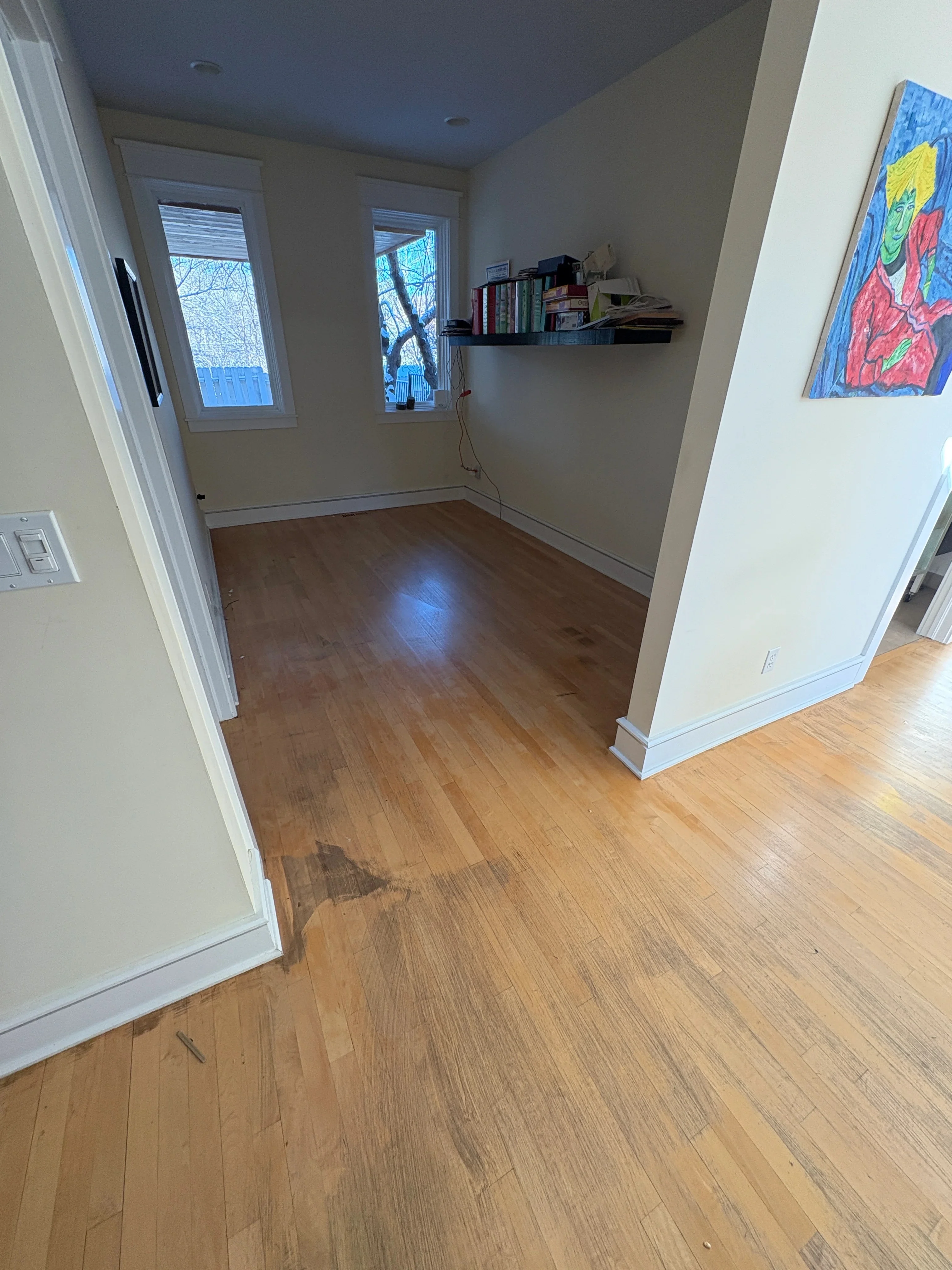 Medium-tone hardwood flooring with white trim and baseboards in open room