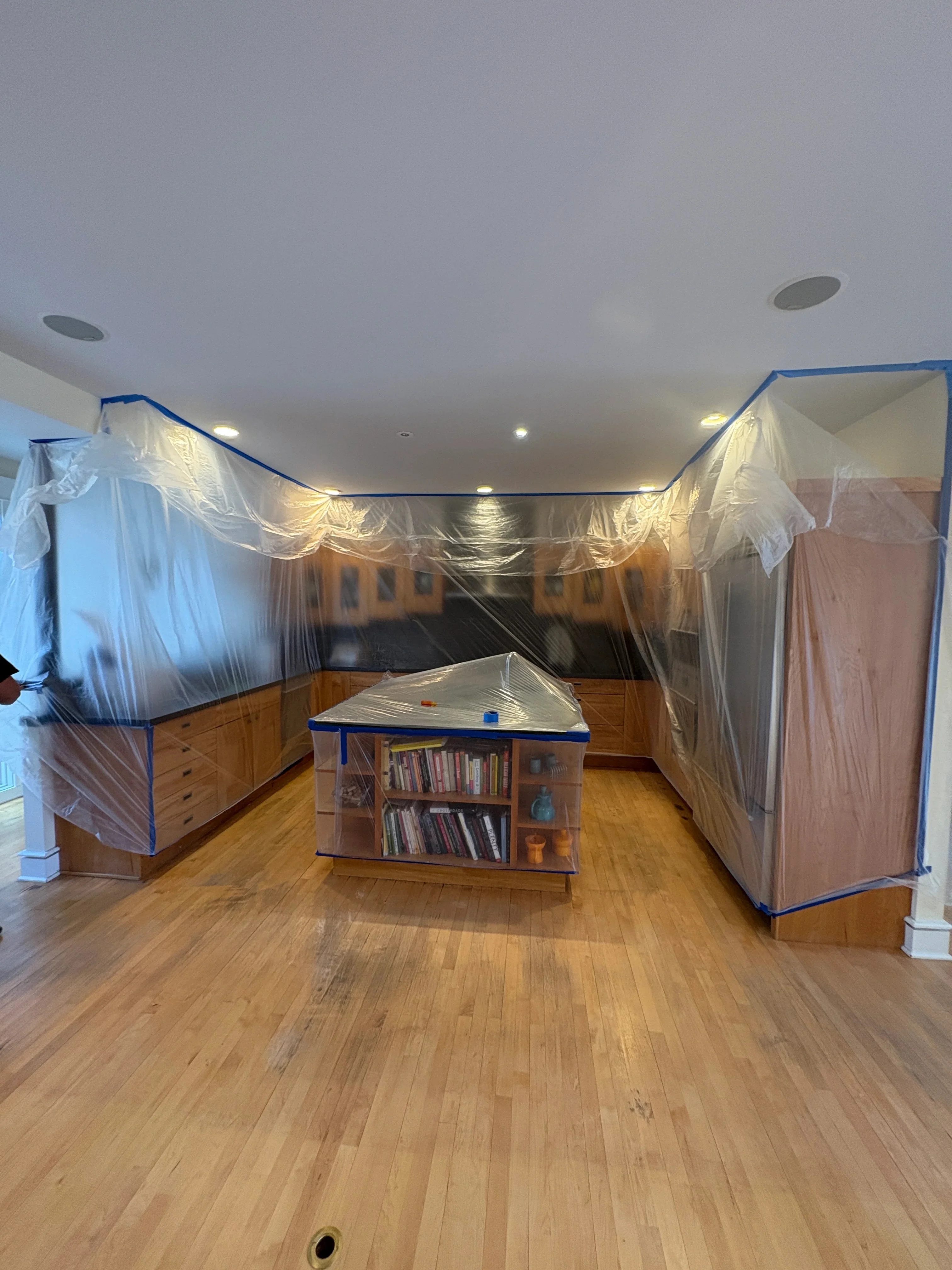 Hardwood floor protected with plastic sheeting and blue tape during interior renovation project
