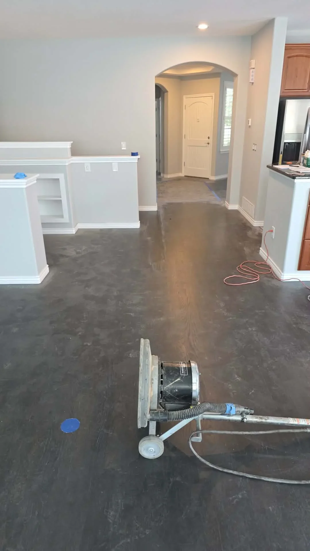 Dark stained hardwood flooring in kitchen with white cabinetry and arched entryway