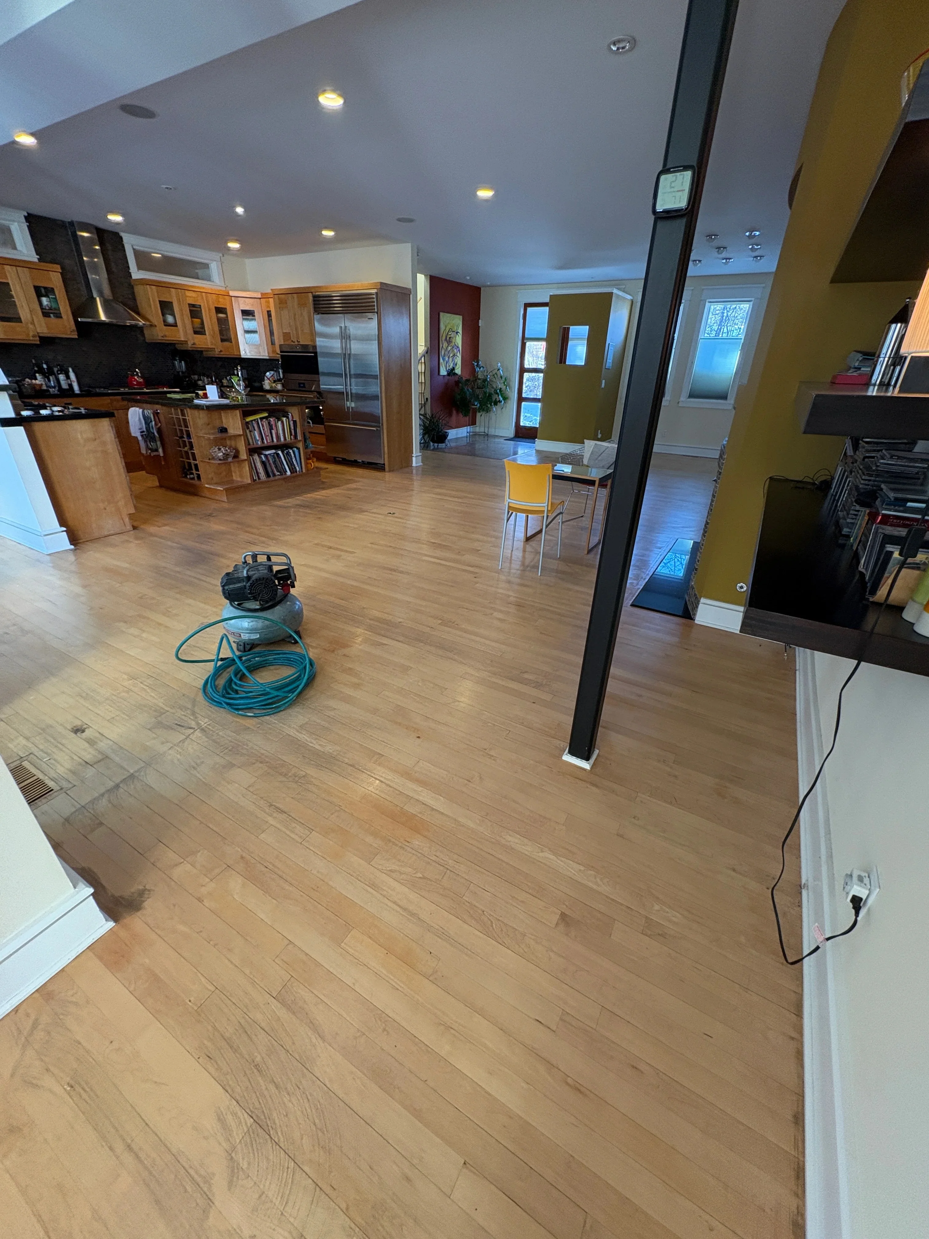 Light oak hardwood flooring installed in open-concept kitchen and living area with wood cabinetry
