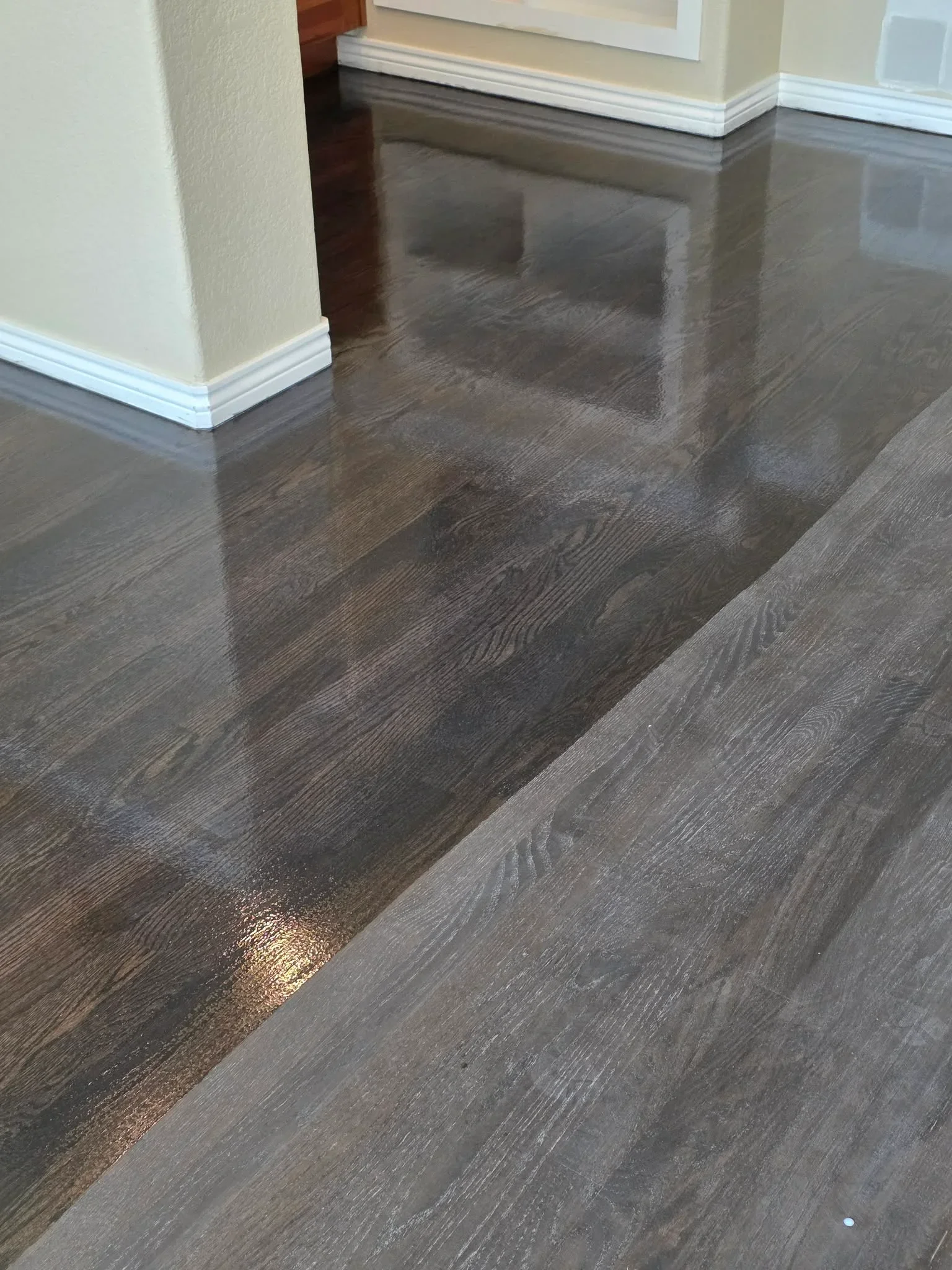 Dark stained hardwood flooring with white baseboards and trim in open room