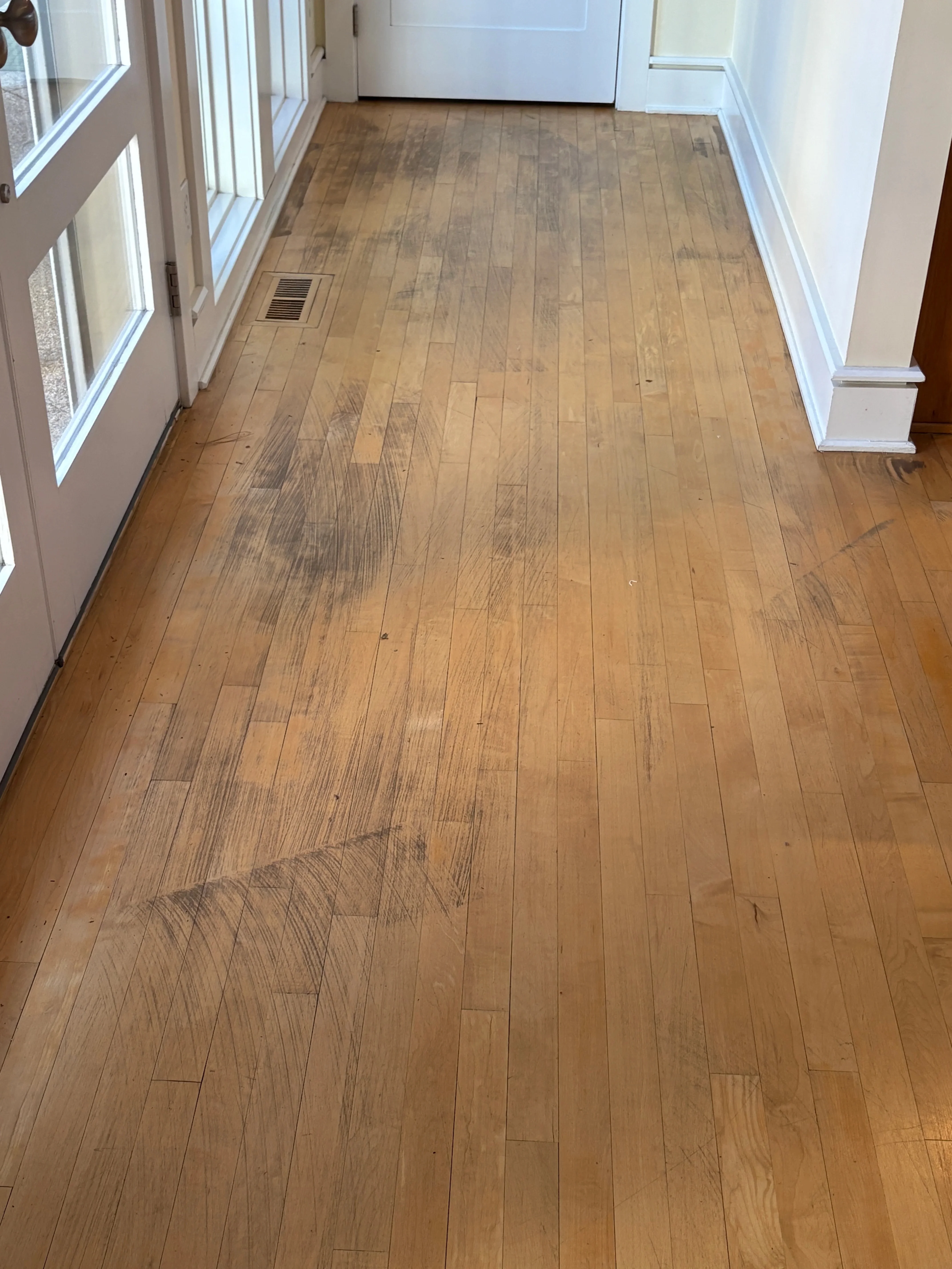 Light oak hardwood flooring with straight plank layout, white baseboards and trim in residential hallway